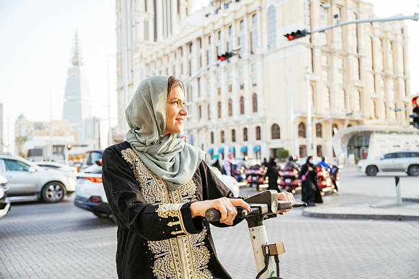 istock Smiling Arabic woman - commuter using electric scooter in the downtown 2234845708
