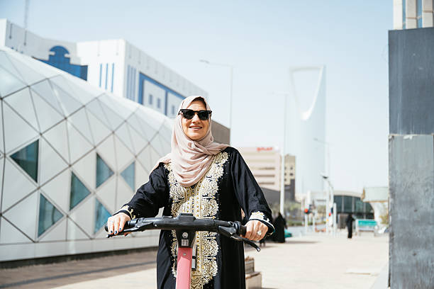 istock Smiling Arabic woman - commuter using electric scooter in the downtown 2234845769