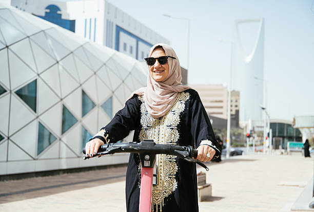 istock Smiling Arabic woman - commuter using electric scooter in the downtown 2234845772