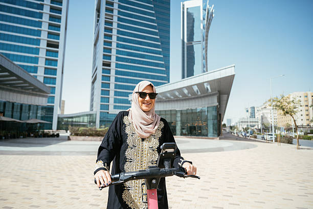 istock Smiling Arabic woman - commuter using electric scooter in the downtown 2234845820