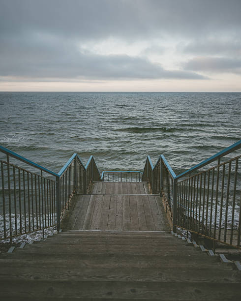 A lone staircase leading directly into the calm sea, creating a serene and minimalist coastal scene. Perfect for travel, nature, and lifestyle projects, evoking peace, reflection, and the beauty of untouched shores.