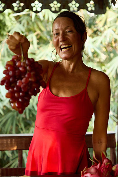 Smiling woman in red holding fresh grapes in a natural outdoor setting