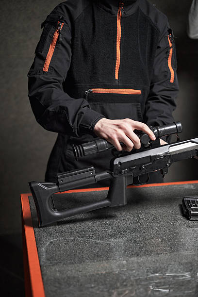 istock Young Adult Man Assembling Rifle Scope on Table Indoors 2234849384