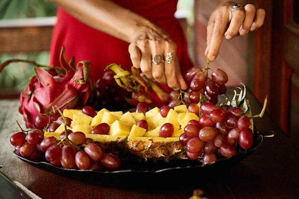 Close-up of fruit platter with hands arranging grace and tropical fruits