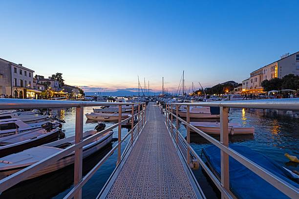 Scenic sunset at marina in Malinska Krk with boats and evening lights reflecting on water