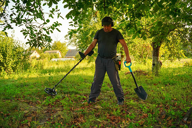 istock A dedicated treasure hunter is using a metal detector and a shovel in a vibrant, sunlit field surrounded by trees. The atmosphere is peaceful and filled with anticipation 2234850381