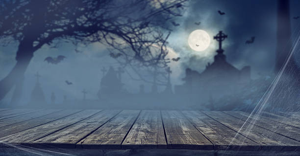 istock Stage horror (or Halloween) background with old wooden surface and horror and Halloween attributes in the background - bats, fog, cemetery crosses and ominous full moon. 2234851153