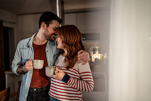 istock Happy young couple embracing and drinking coffee in kitchen 2234853222