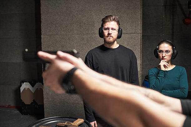 istock Young Man and Woman Observing Firearm Training at Shooting Range 2234853943