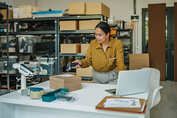 Asian woman efficiently managing inventory and preparing shipments in a warehouse office environment