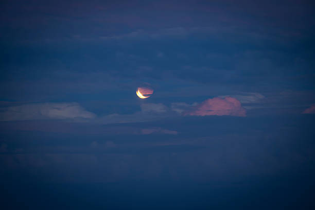 A beautifully illuminated crescent moon shines through soft clouds, creating a tranquil atmosphere in the night sky, enhancing the tranquility of the evening.