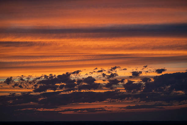Sky transforms with vibrant hues during a stunning sunrise over the horizon, illuminating the clouds with warm colors and setting the mood for a new day
