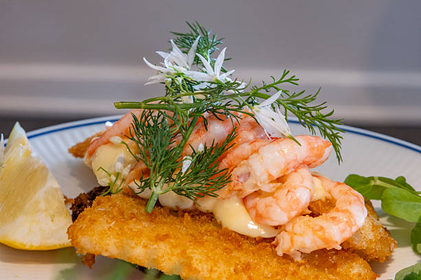 A typical Scandinavian meal design; a shrimp dish. Fresh ocean shrimp placed on top of a pan-fried fish fillet and garnished with various herbs.