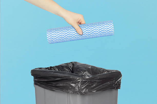 istock throwing a roll of disposable kitchen towels into the trash, outstretched hand with a roll of disposable kitchen towels in front of a trash can 2234859465