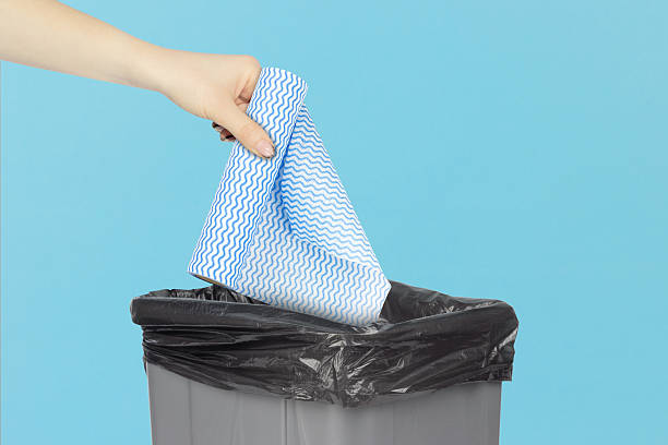 istock throwing a roll of disposable kitchen towels into the trash, outstretched hand with a roll of disposable kitchen towels in front of a trash can 2234859486