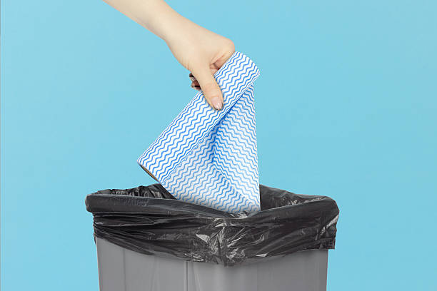 istock throwing a roll of disposable kitchen towels into the trash, outstretched hand with a roll of disposable kitchen towels in front of a trash can 2234859489