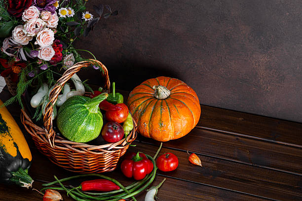Autumn harvest still life, background with empty copy space. Vegetables harvest in wicker basket. Squash, vegetable autumn fruit, tomatoes, and eggplants on a wooden table. Decoration fall design.