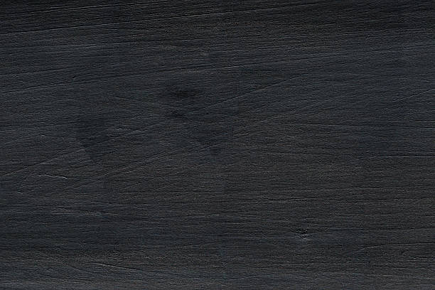istock Splintered charcoal timber, scarred by fire, displays a rough knot in this minimal top-down macro shot. 2234863921