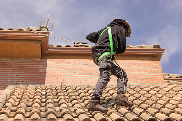Professional roofer working on a residential clay tile roof, installing a coaxial boiler flue with safety harness. Home improvement, construction safety, and roofing services concept.