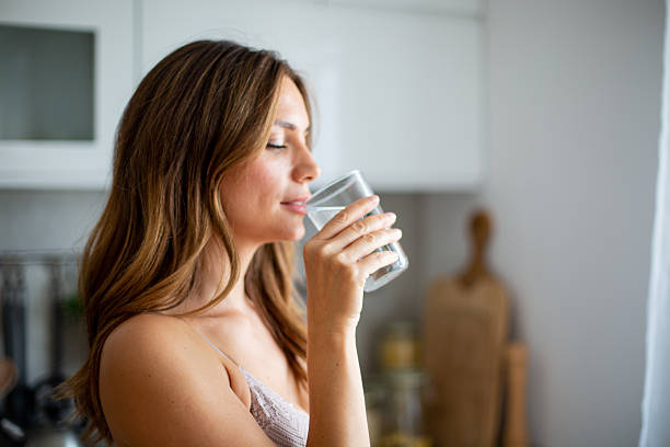 istock Young woman drinking fresh water in the kitchen 2234865554