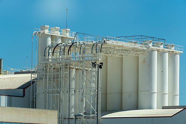 A large white industrial building with a blue sky in the background. The building is made of white and red materials