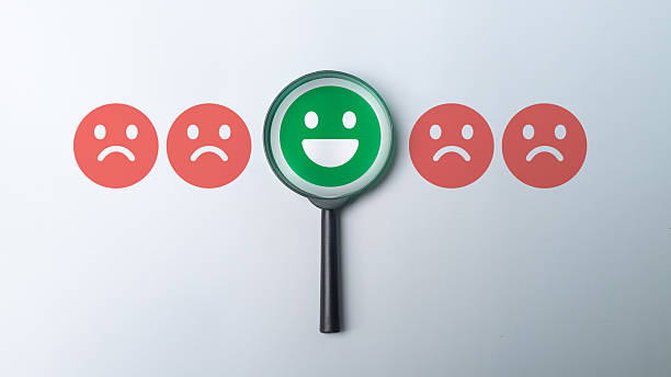 istock Customer feedback and sentiment analysis concept with a magnifying glass highlighting a happy face among sad faces. Idea of customer satisfaction, emotion recognition, and business experience analytics. 2234869781