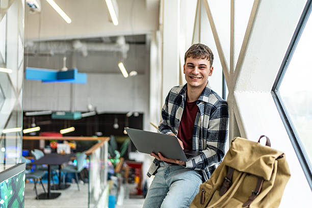 istock Smiling student working on laptop in university hallway 2234870121