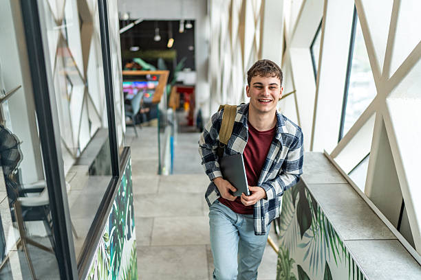 istock Smiling student walking down the stairs at university holding a tablet 2234870181