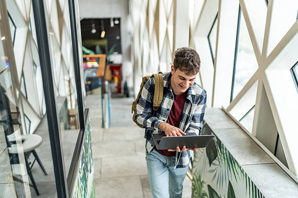 istock Smiling young man walking and using laptop in modern building 2234870185