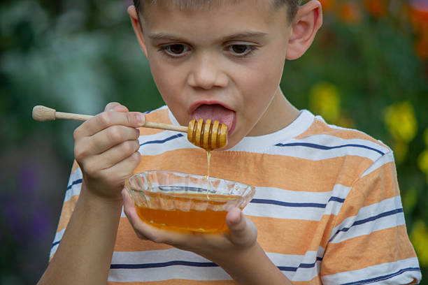 istock Boy eating honey on a garden background. Selective focus 2234871221