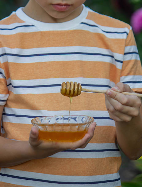 istock Boy eating honey on a garden background. Selective focus 2234871227