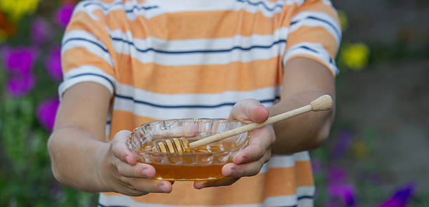 istock Boy eating honey on a garden background. Selective focus 2234871238