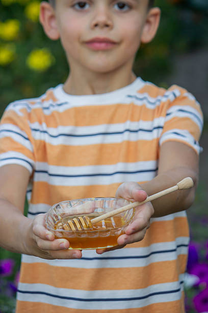 istock Boy eating honey on a garden background. Selective focus 2234871242