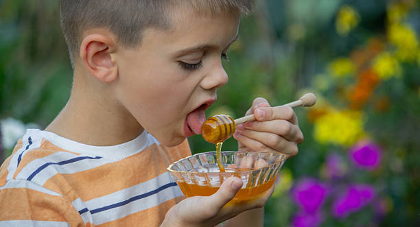 istock Boy eating honey on a garden background. Selective focus 2234871246