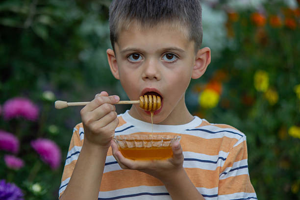 istock Boy eating honey on a garden background. Selective focus 2234871255