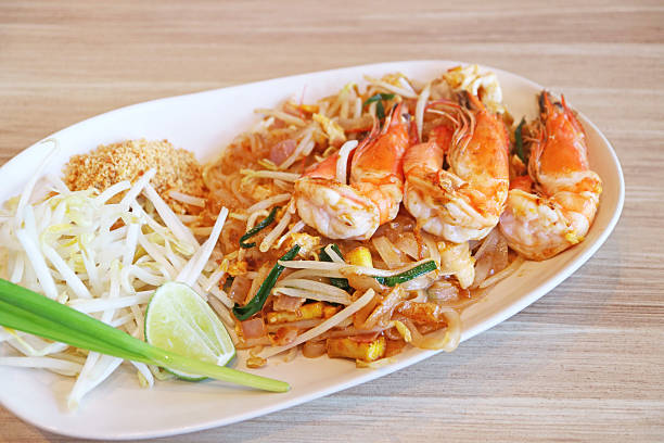 Mouthwatering Pad Thai Noodle Topped with River Prawns Served on Wooden Table