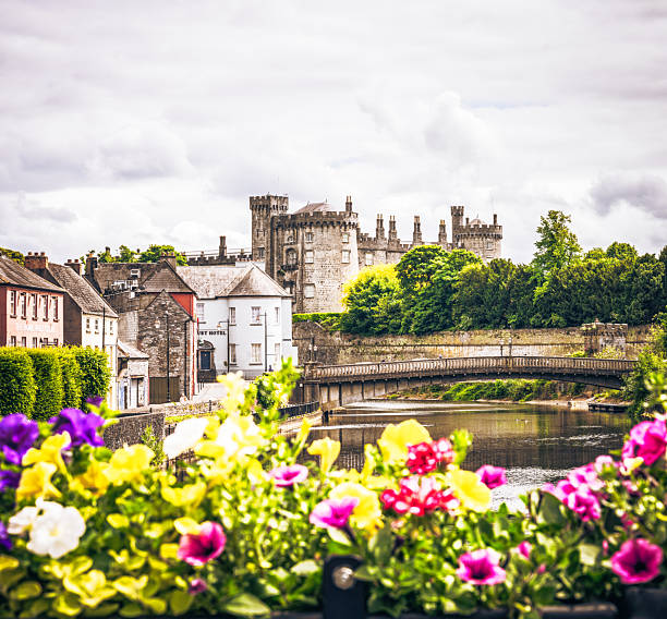 Kilkenny, Ireland - Defocused flowers on a bridge in the foreground over the River Nore in Kilkenny, with Kilkenny Castle on the horizon.