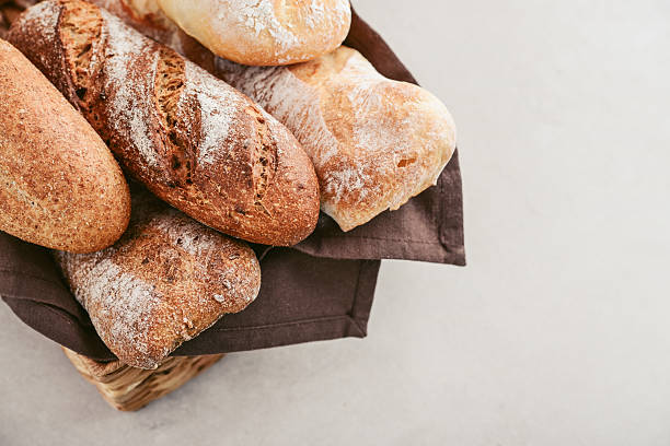 Assorted bakery products including loafs of bread,  baguette and rolls in basket, top view