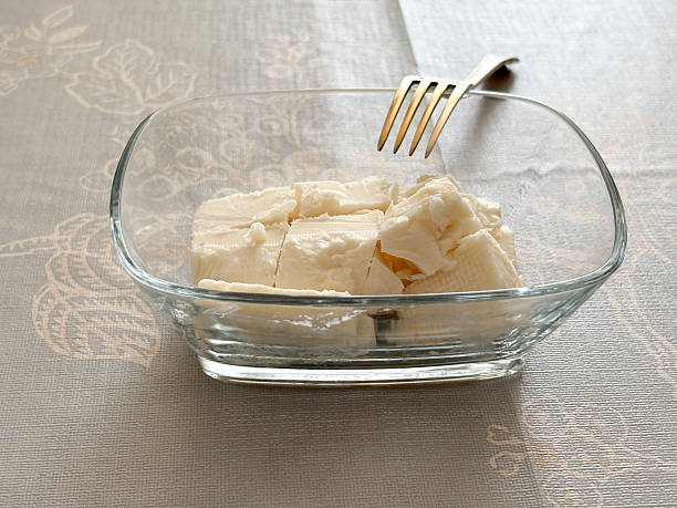 White cheese slices in a glass bowl with a fork. Breakfast white cheese on the table