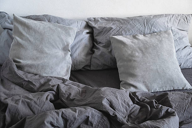 istock Grey pillows and crumpled linen bedding on bed. 2234879643