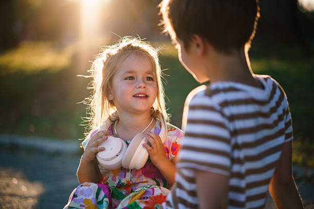 Sibling children are playing in dust sitting on summer dirt road