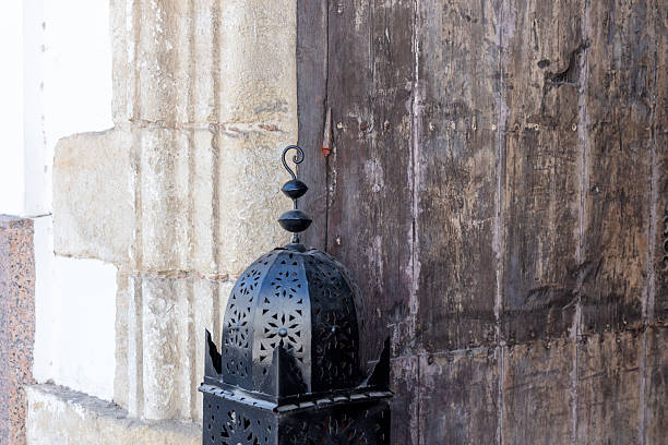 Black iron lantern detail beside historic wooden door in Arcos de la Frontera, Andalusia, Spain. .