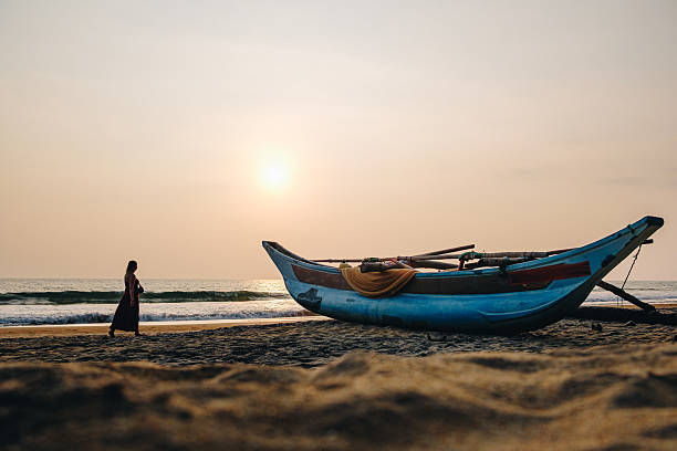 Young woman and boat on beach at sunset, Galle