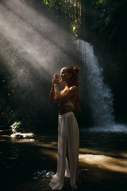 istock Serene woman meditating by tropical waterfall surrounded by nature and sunlight 2234884774