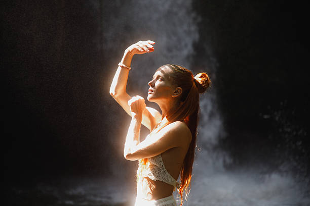 istock Young woman illuminated by sunlight in a serene waterfall setting 2234884779