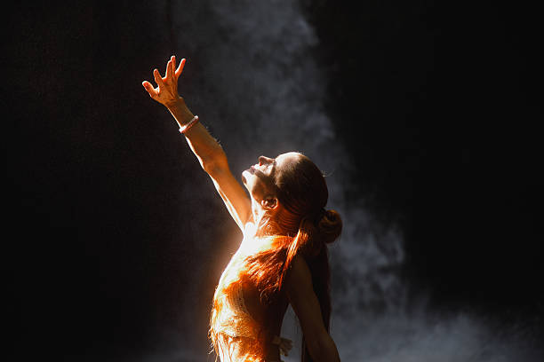 Expressive woman reaching out in dramatic lighting near a misty background