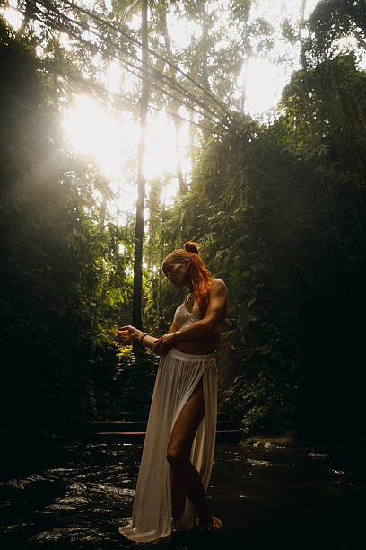 istock Red-haired woman posing in a lush green jungle with streaming sunlight 2234884949
