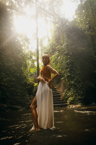 istock Woman in a white dress standing in a serene forest setting 2234884950