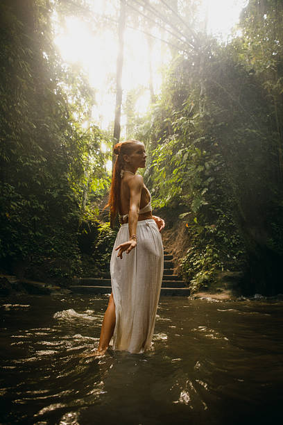 istock Woman exploring a serene jungle stream surrounded by lush greenery and sunlight 2234884958