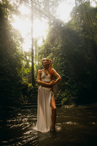 istock Woman standing in serene forest with sunlight filtering through foliage 2234884977